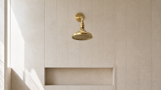 Unlacquered brass rain shower head with a short adjustable wall arm above a shower niche