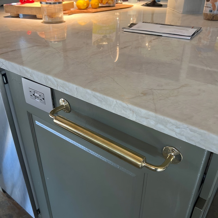 A collection of brass accessories, featuring a cabinet handle with curved ends, a vintage-style wall hook, and an intricately engraved soap dish, combining functionality with elegant craftsmanship.