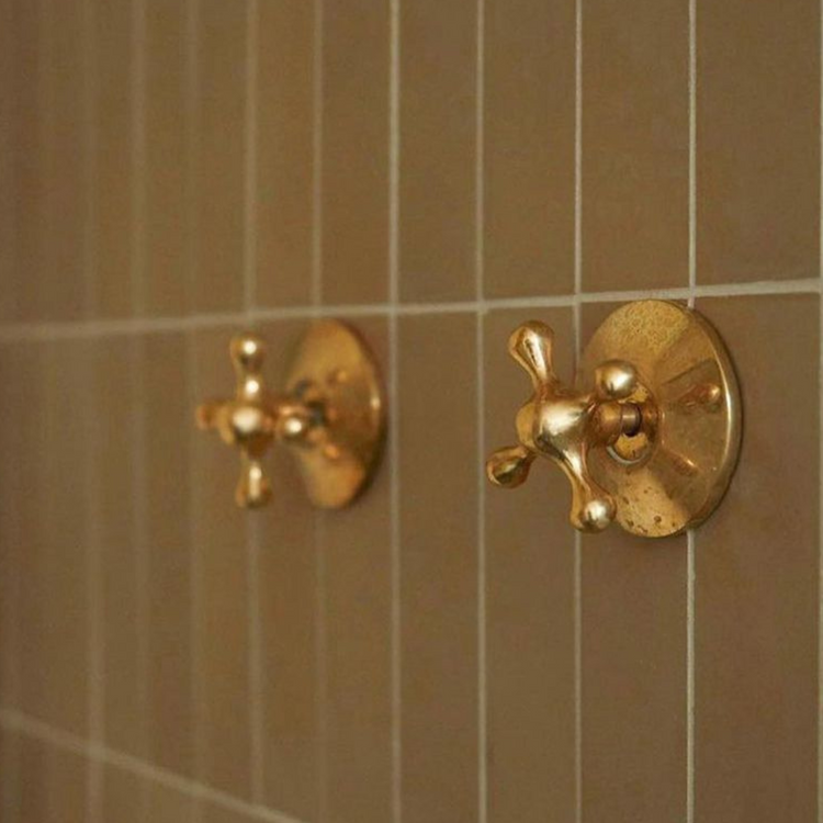 A collection of brass hardware components, including a faucet valve body, cross and lever handles, and decorative escutcheons, showcasing high-quality craftsmanship for plumbing and fixture assembly.