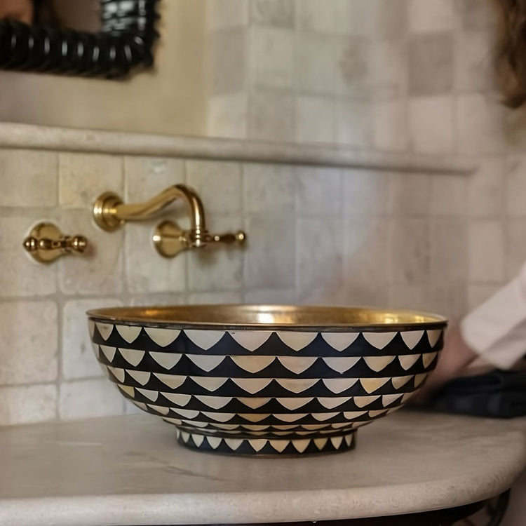 A hammered copper farmhouse sink with a rich, warm finish, seamlessly integrated into a white marble countertop, paired with a matching antique copper bridge faucet for a timeless and elegant kitchen design.